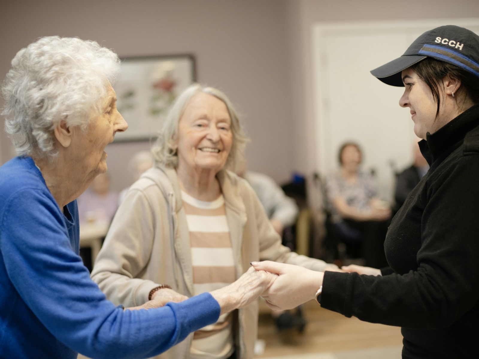 Two older women holding hands with a younger woman
