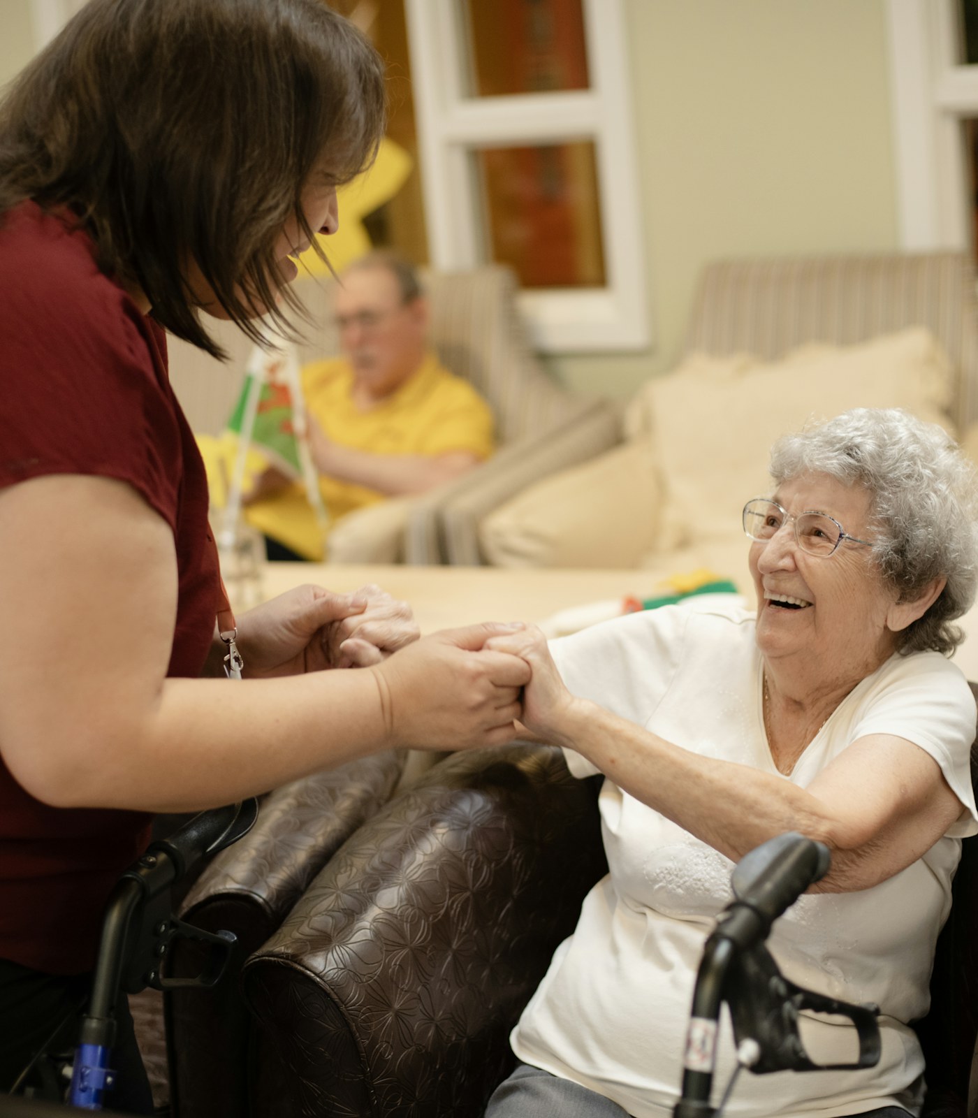 A caregiver walks beside an older woman using a walker at home