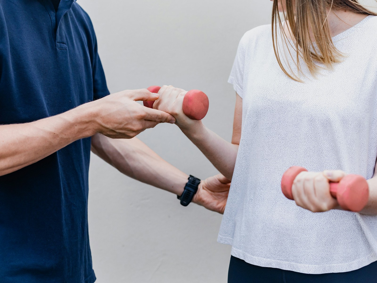 A physical therapist guides a patient through a light dumbbell exercise