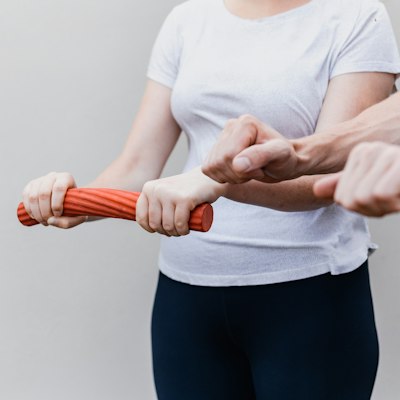 A patient practices a resistance exercise while a therapist supervises